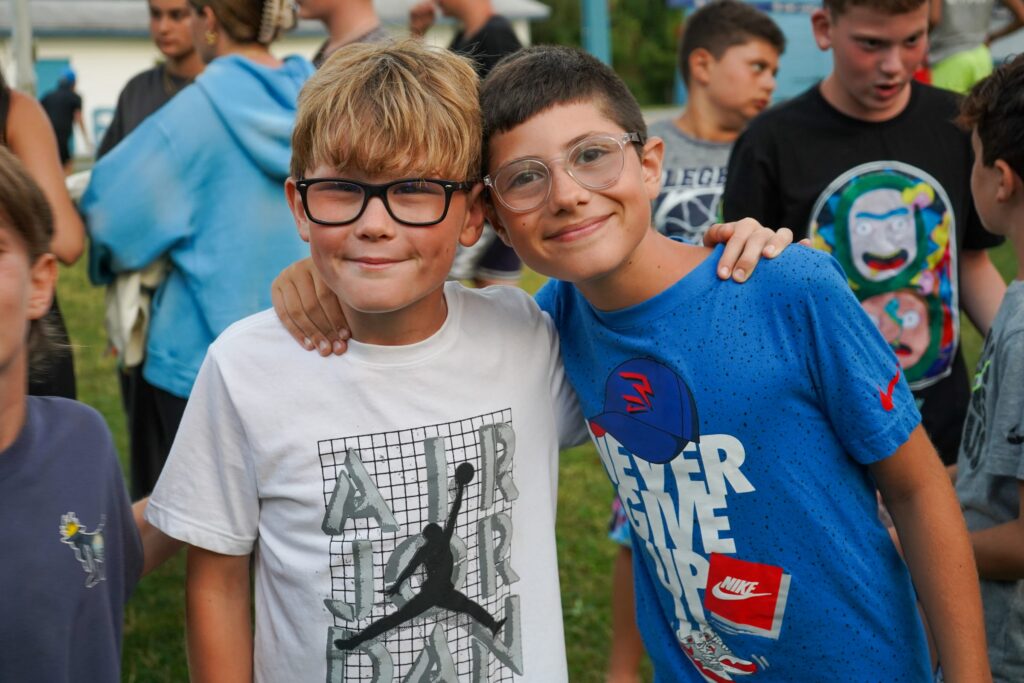 Two boys smiling and posing together at a camp event.