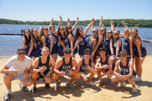 Camp Lakota CIT counselors in training posing together on the sandy beach at Masten Lake during summer camp