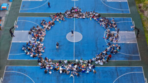 Campers sitting in a circle on the basketball court at Camp Lakota